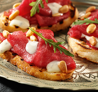 Crostini with carpaccio, rocket and pine nuts