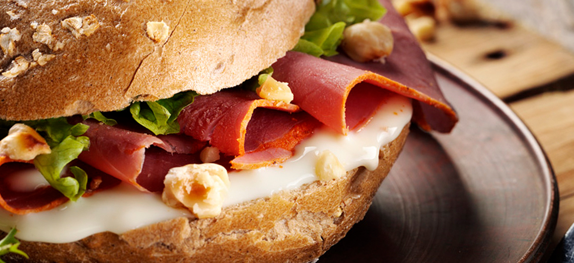 Luxurious brown roll with thinly sliced pastrami and soft Gouda cheese