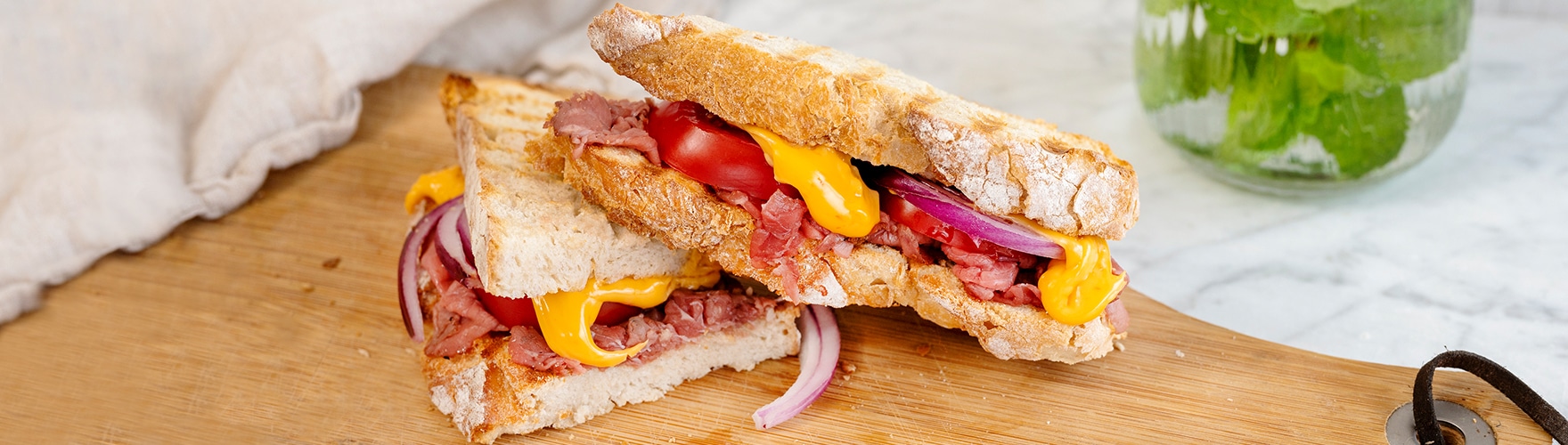 Tosti met pittige plakjes cheddar, rosbief, tomaten en rode ui
